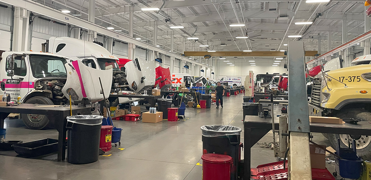 Photo of interior work space with trucks being worked on.